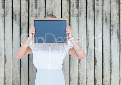 Busines woman with blackboar in front of the head. Wood background