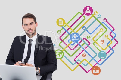 Portrait of businessman using phone and laptop with icons in background