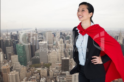 Happy businesswoman in super hero costume standing over city