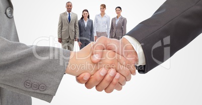 Cropped image of businessmen doing handshake with employees in background
