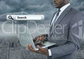 Businessman holding laptop with Search Bar with city background