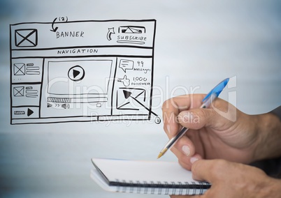 Hands with pen and notepad against website mock up against blurry grey wood panel