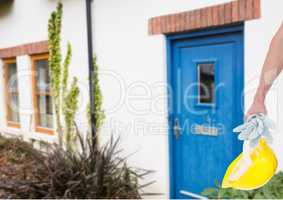 hand with yellow hat in front of blue door real house.