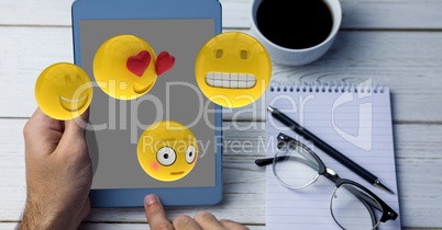 Close-up of hands using tablet PC while emojis flying over table