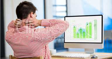 Rear view of stressed businessman looking at graph on computer