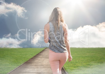 Woman walking up path to blue sky sun