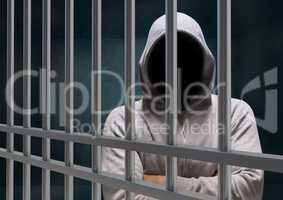 Anonymous Criminal in hood behind prison bars