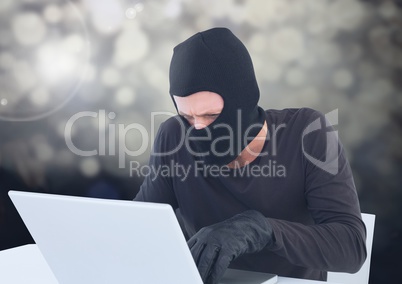 Criminal in balaclava with laptop in sparkling lights