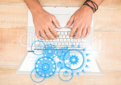 Overhead of hands on laptop with blue cog graphics