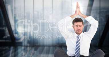 Business man meditating with hands over head against dark blue blurry window