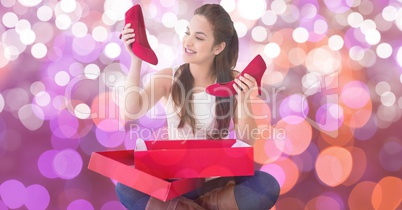 Happy woman looking at new red shoes over bokeh