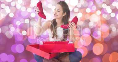 Happy woman looking at new red shoes over bokeh