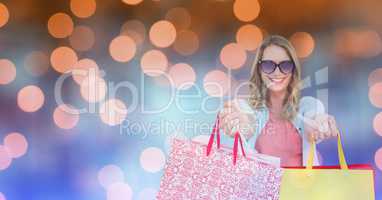 Happy woman showing shopping bags over bokeh