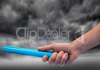 Hand with blue baton and lightning against stormy sky