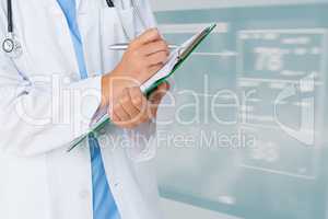 Midsection of doctor writing on clipboard