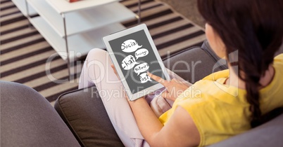Woman looking at speech bubbles on digital tablet at home