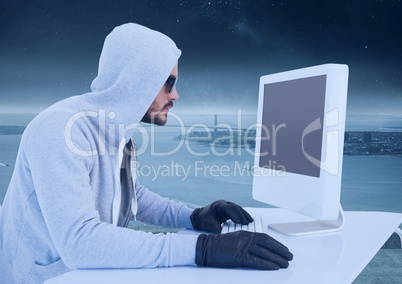 Criminal Man in hood on computer in front of landscape