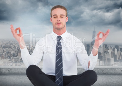 Business man meditating against grey skyline and clouds