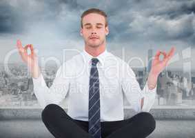Business man meditating against grey skyline and clouds