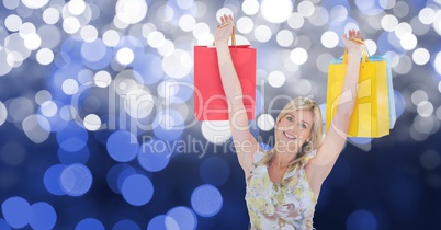 Happy woman with arms raised holding shopping bags