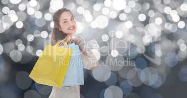 Beautiful woman carrying shopping bags over bokeh