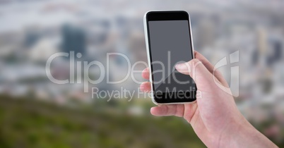 Hand with phone against blurry skyline