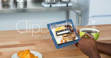 Online food app on tablet PC held by man holding coffee