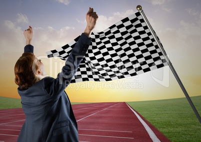 Business woman cheering on track against checkered flag and evening sky