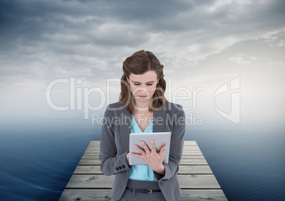 woman on tablet on boardwalk by sea