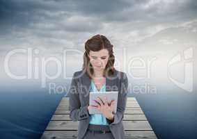 woman on tablet on boardwalk by sea