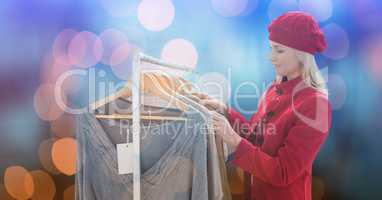 Woman choosing tops over bokeh background