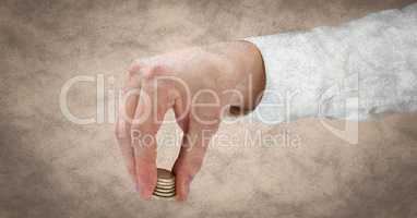 Hand with coins against cream grunge background
