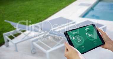 Hands using smart home application on digital tablet at poolside
