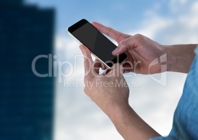 Hands with phone against sky and blurry building