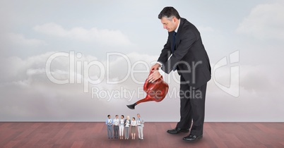 Large businessman watering employees against sky