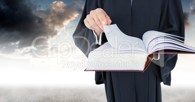 Judge holding book in front of sky clouds