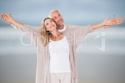 Affectionate couple with arms outstretched standing at beach