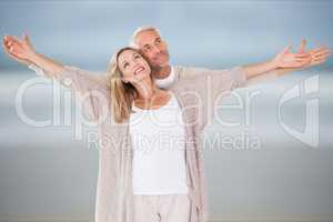 Affectionate couple with arms outstretched standing at beach