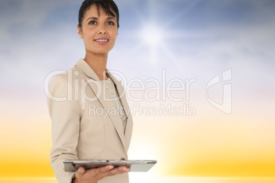 Composite image of woman using a tablet against sky background