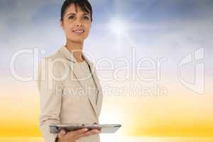 Composite image of woman using a tablet against sky background