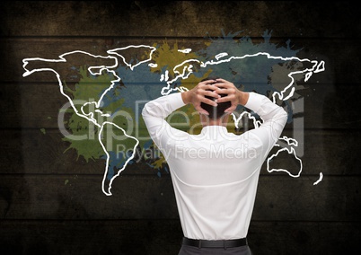 Businessman holding head looking at Colorful Map with paint splatters on wall background
