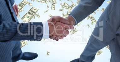 Midsection of business people shaking hands with money in background