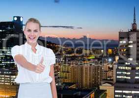 Business woman in front of the city at night with thumb up