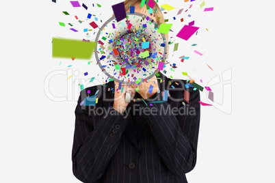Businesswoman using megaphone emitting confetti against white background