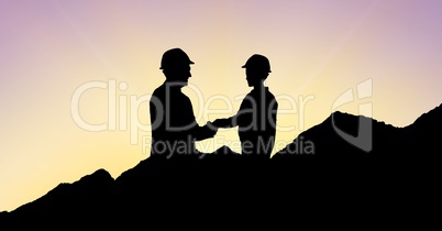 Silhouette architects shaking hands on mountains during sunset