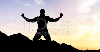 Silhouette man with arms raised on mountain during sunset