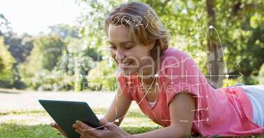 Female student using tablet PC while lying on grass