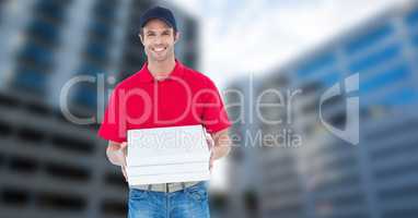 Portrait of smiling pizza delivery man holding pizza box against buildings