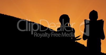 Silhouette children reading books on hill during sunset