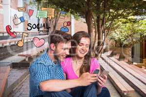 Happy young couple using social media on mobile phones by icons